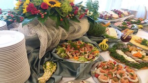 A buffet table with various food items, a floral centerpiece, and neatly stacked plates. - Geovita Krynica Zdroj (Krynica-Zdroj)