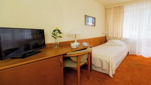 A hotel room with a television, a desk with a lamp, a chair, a bed, and a window with curtains. - Geovita Krynica Zdroj (Krynica-Zdroj)