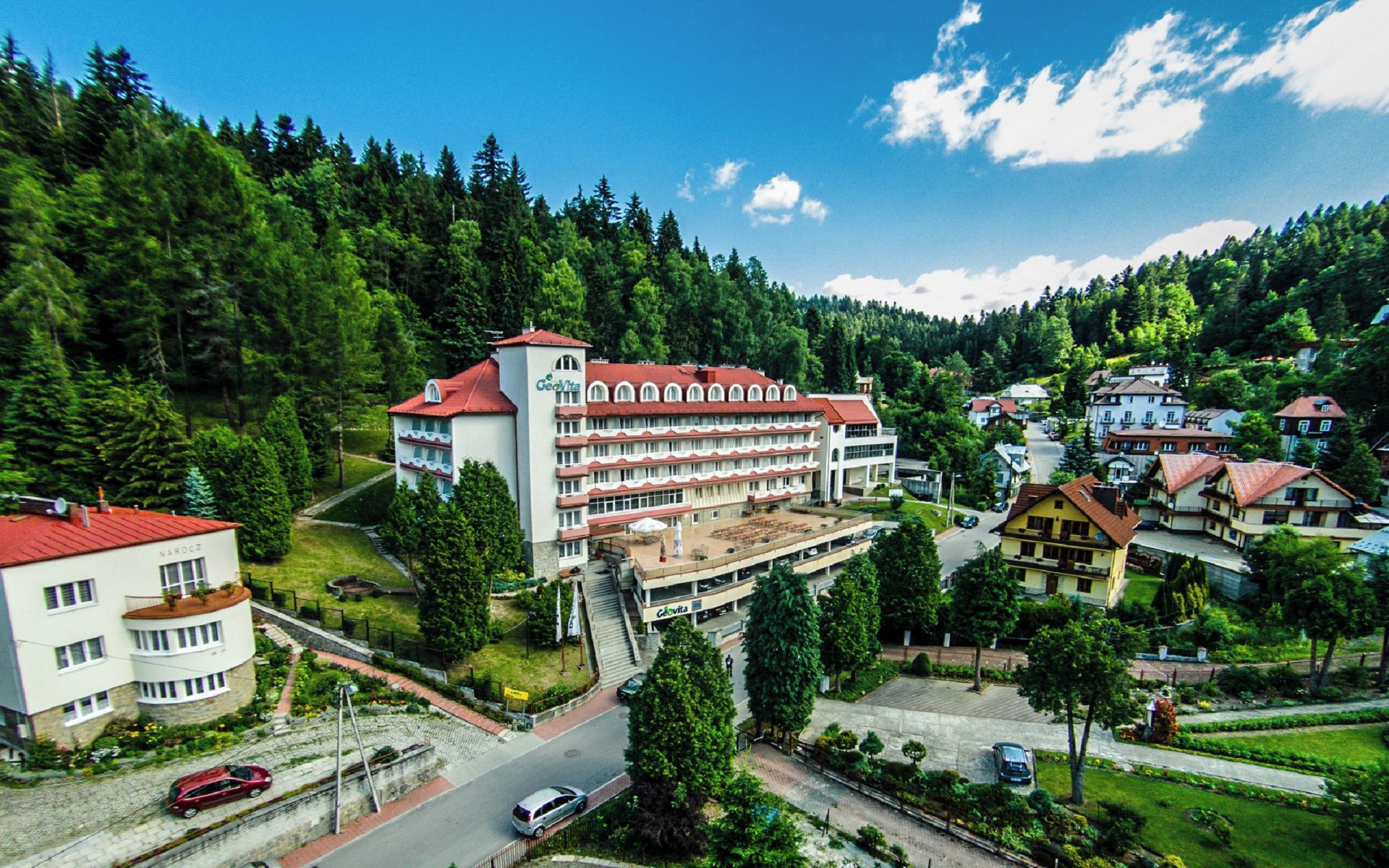 A hotel with a red roof, multiple floors, and a central courtyard.