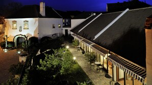 A courtyard with a white building, outdoor seating, and a covered area. - Herberge an der Nikolauszeche (Purbach am Neusiedlersee)