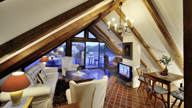 A cozy attic living room with a TV, seating, and a view of the outdoors. - Herberge an der Nikolauszeche (Purbach am Neusiedlersee)