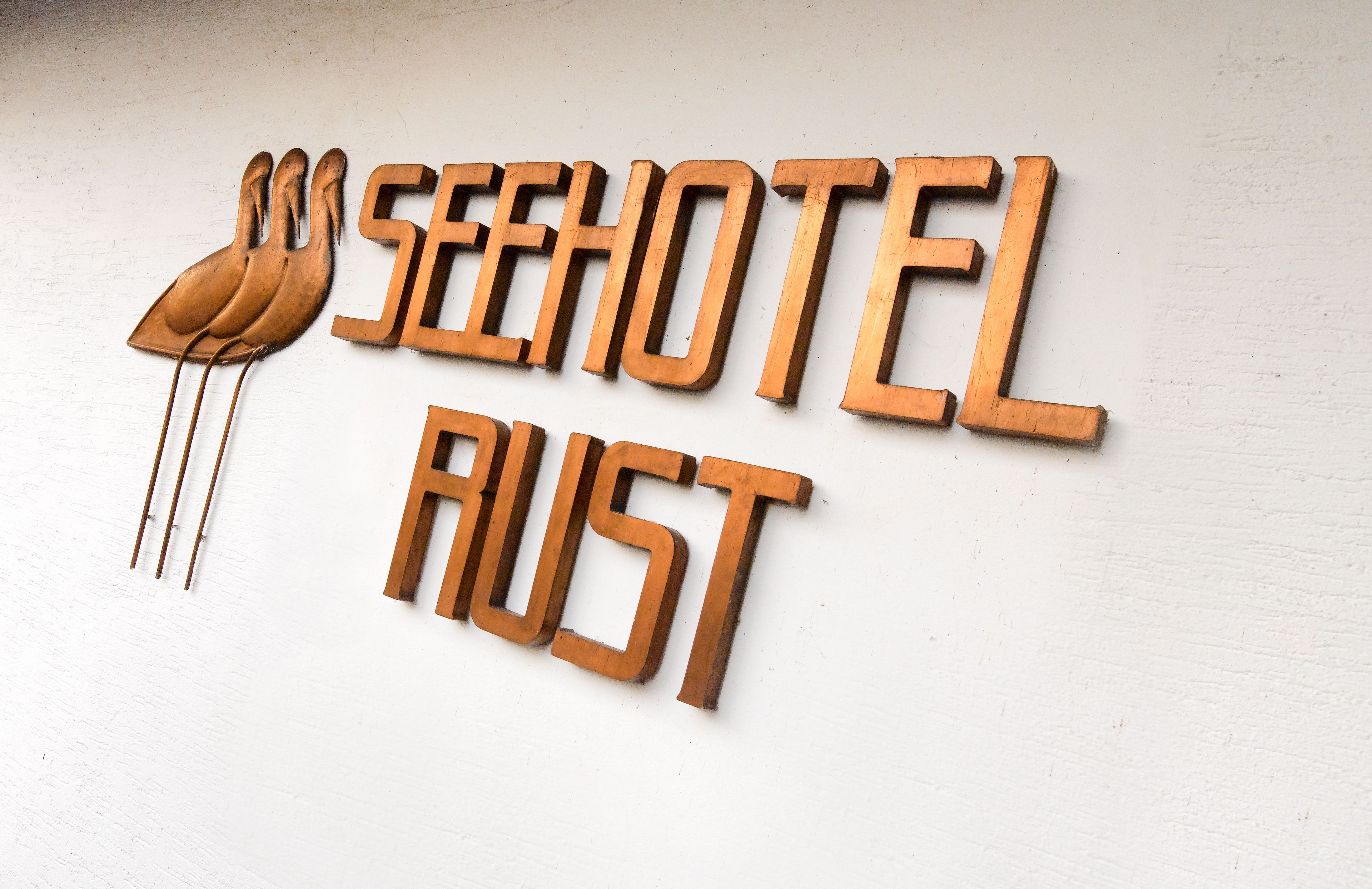 A wooden sign with the text "SEEHOTEL RUST" and a stylized bird design.