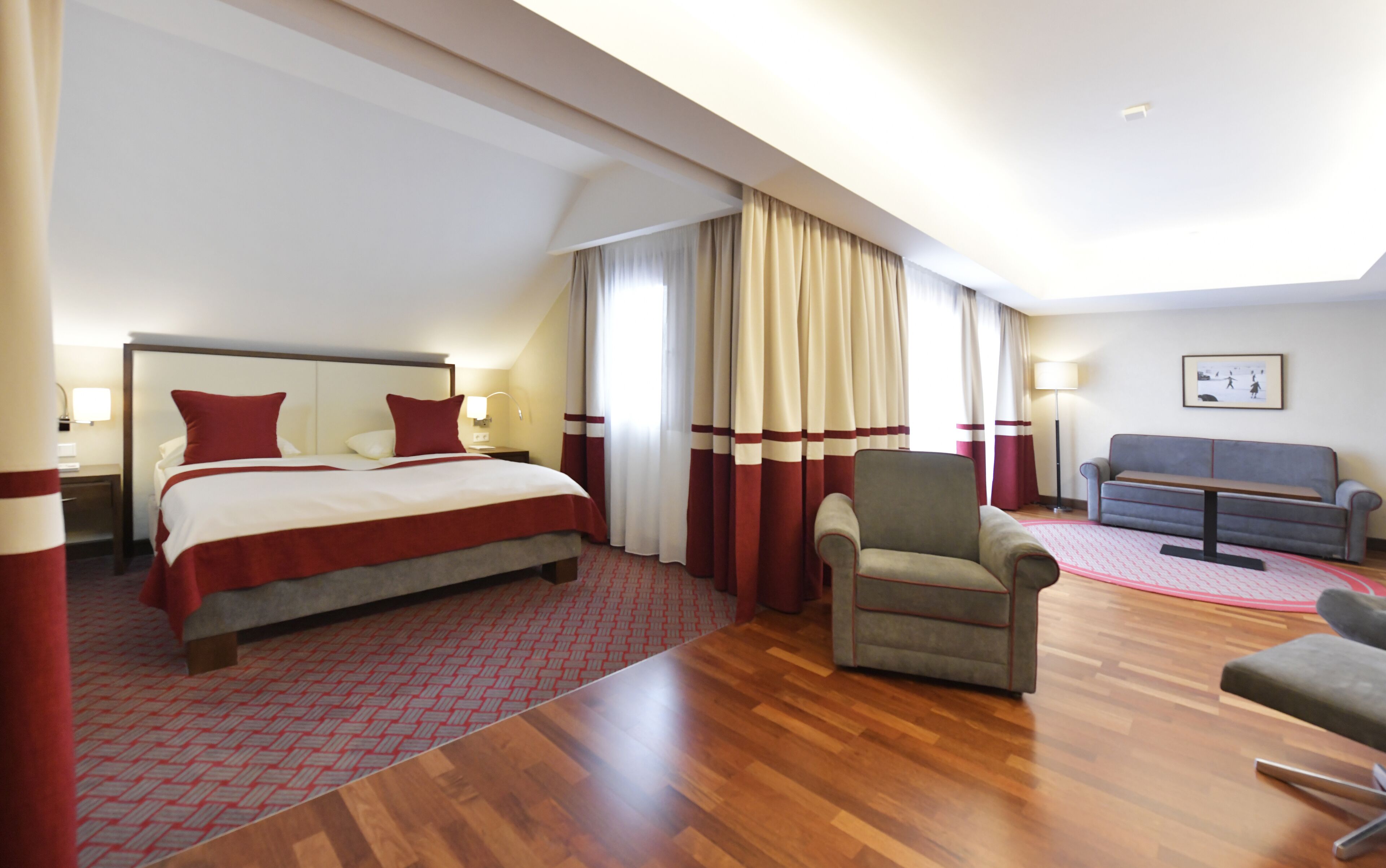 A hotel room with a large bed, a chair, a sofa, and a desk.
