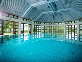 Una piscina interior con techo alto y ventanas amplias.