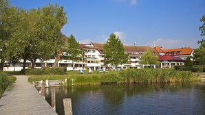 A lakeside hotel with a wooden dock, lounge chairs, and a view of the water. - Seehotel Rust (Rust)