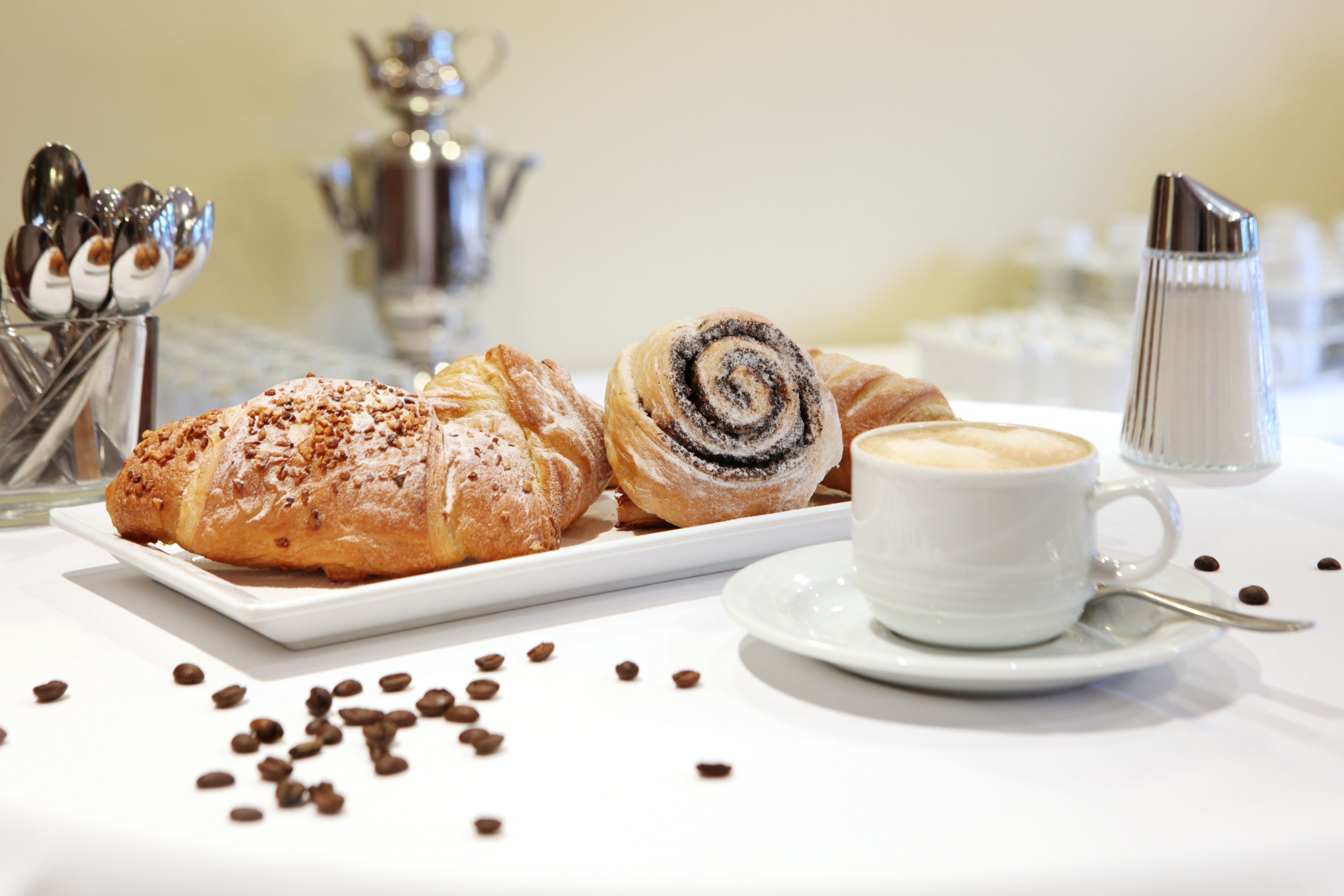 A table with pastries, coffee, and scattered coffee beans.