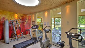 A gym with cardio machines, weight equipment, and a mirrored wall.