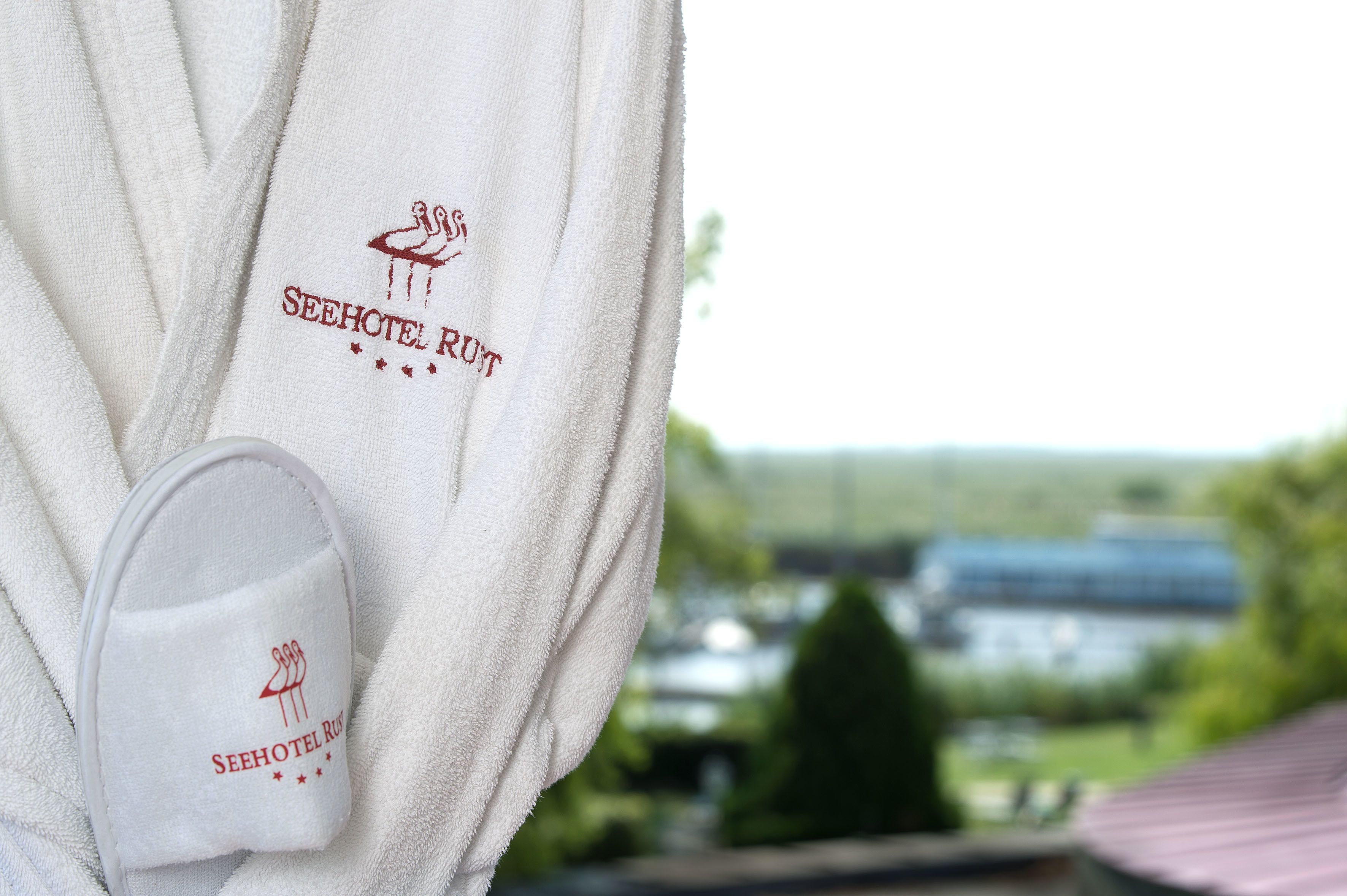 A white towel with a logo and text, and a white bath mat with the same logo and text.