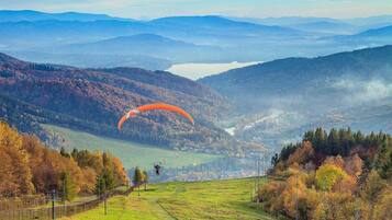 A mountainous landscape with a person paragliding over a valley.