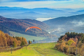 A mountainous landscape with a person paragliding over a valley. - Hotel Relax (Kety)