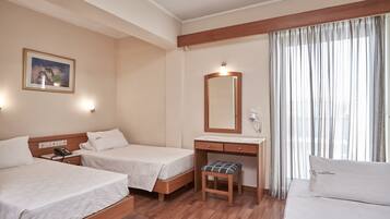 A hotel room with two beds, a desk, a chair, a mirror, and a window with curtains.