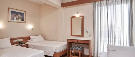 Une chambre d’hôtel avec deux lits, un bureau, une chaise, un miroir et une fenêtre avec des rideaux.