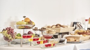 A buffet table with various food items including fruits, pastries, and beverages.