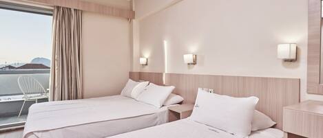 A hotel room with two beds, a window with curtains, and a view of the city.