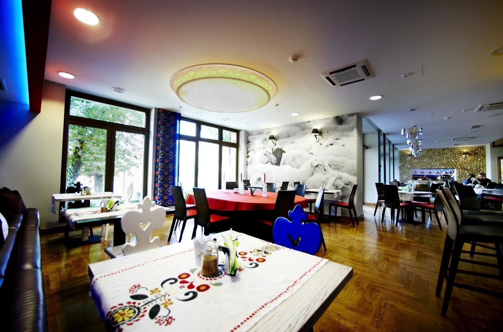 A dining area with tables set for meals, large windows, and a ceiling with recessed lighting.