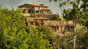 Una villa en una ladera con varias construcciones, rodeada de abundante vegetación.