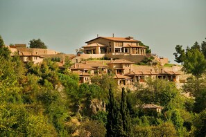 A hillside property with multiple houses, featuring stone walls and terraced roofs.