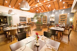 A restaurant with wooden ceilings and tables set for dining.