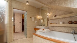 A modern bathroom with a large bathtub, a glass shower enclosure, and a vanity with a mirror. - Hotel Badura (Wadowice)