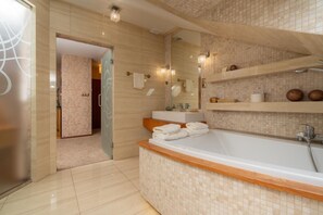 A modern bathroom with a large bathtub, a glass shower enclosure, and a vanity with a mirror. - Hotel Badura (Wadowice)