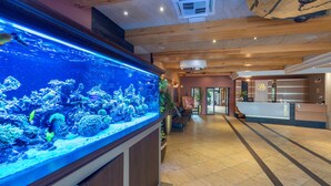 A reception area with a large aquarium, wooden ceiling, and a reception desk. - Hotel Badura (Wadowice)