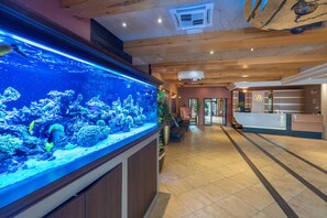 A reception area with a large aquarium, wooden ceiling, and a reception desk. - Hotel Badura (Wadowice)