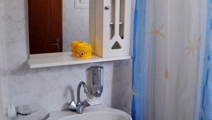 A bathroom with a white sink, a mirror, and a shower curtain with a starfish pattern. - Atlantis Place Milos (Milos)