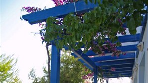 A covered outdoor seating area with blue columns, a concrete bench, and a table. - Atlantis Place Milos (Milos)