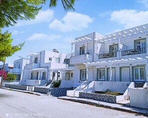 A row of modern, white buildings with balconies and a clear sky. - Atlantis Place Milos (Milos)