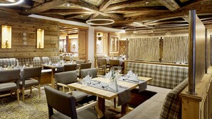 Un restaurante con vigas de madera, mesas dispuestas con manteles blancos y una zona de bar.
