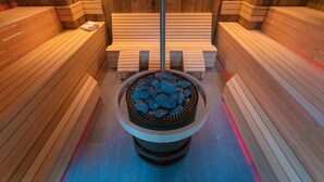 Una sauna con bancos de madera y un elemento calefactor central de piedra.