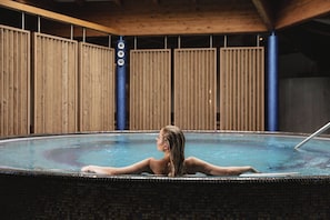 Una piscina techada, una piscina al aire libre, sombrillas
