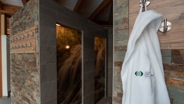 Un baño con pared de piedra, un perchero para toallas y una puerta de ducha de vidrio.