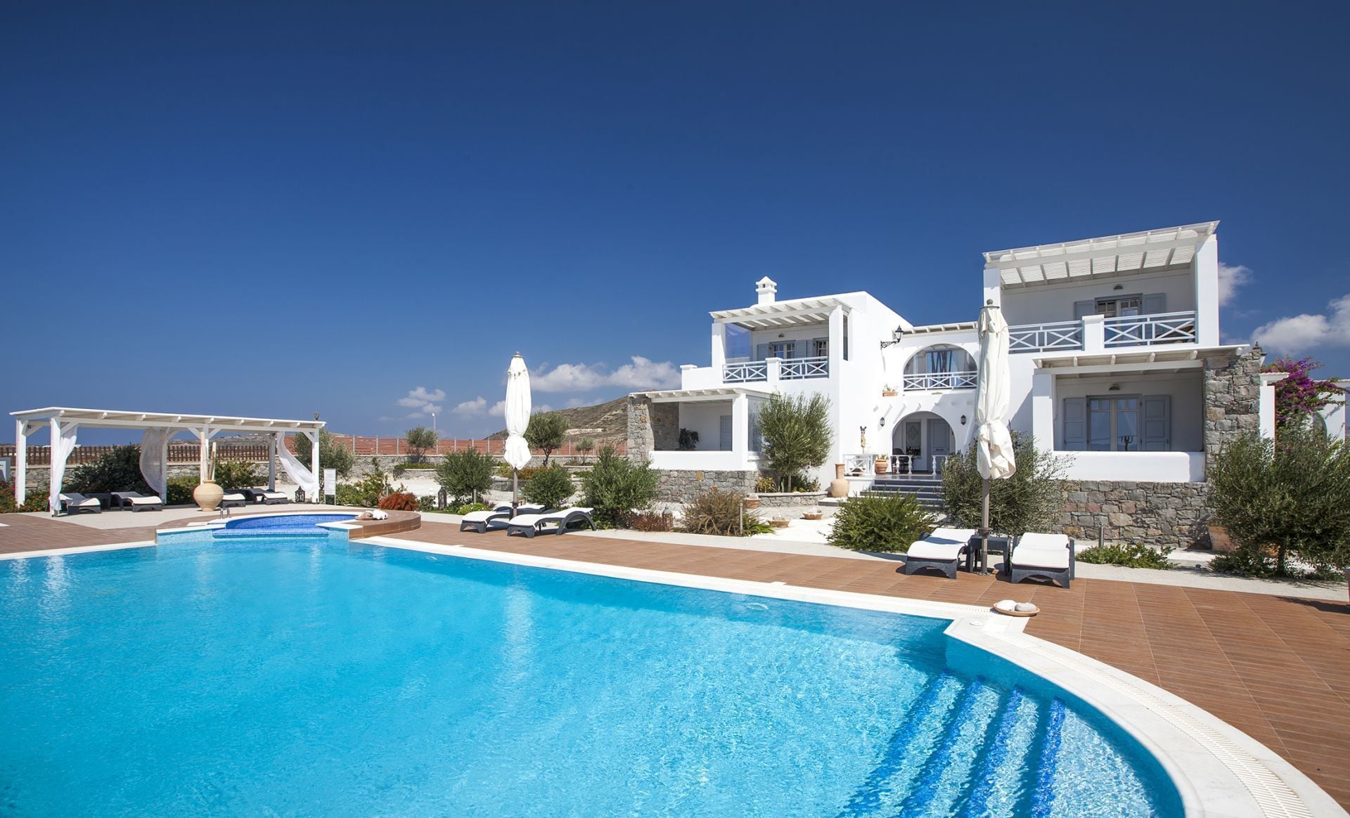 Un resort con una gran piscina, edificios blancos y un cielo azul despejado.