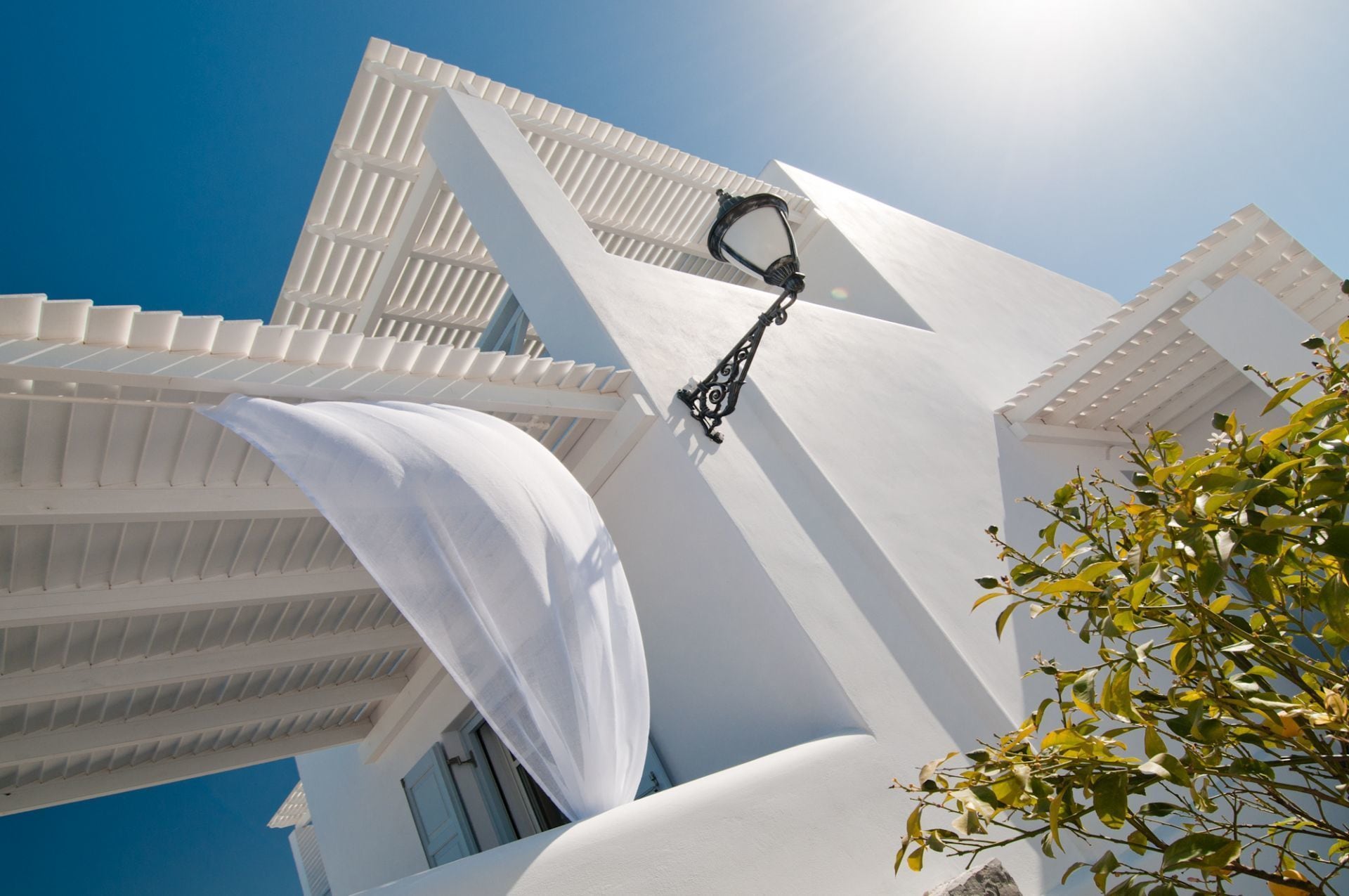 A white building with a modern design, featuring a prominent white awning and a black outdoor light fixture.