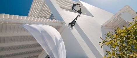 A white building with a modern design, featuring a prominent white awning and a black outdoor light fixture.