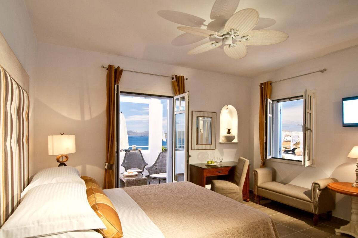 Una habitación de hotel con cama, escritorio, silla y vistas al mar.
