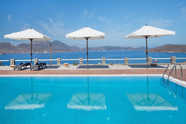 Una piscina al aire libre, sombrillas, sillones reclinables de piscina