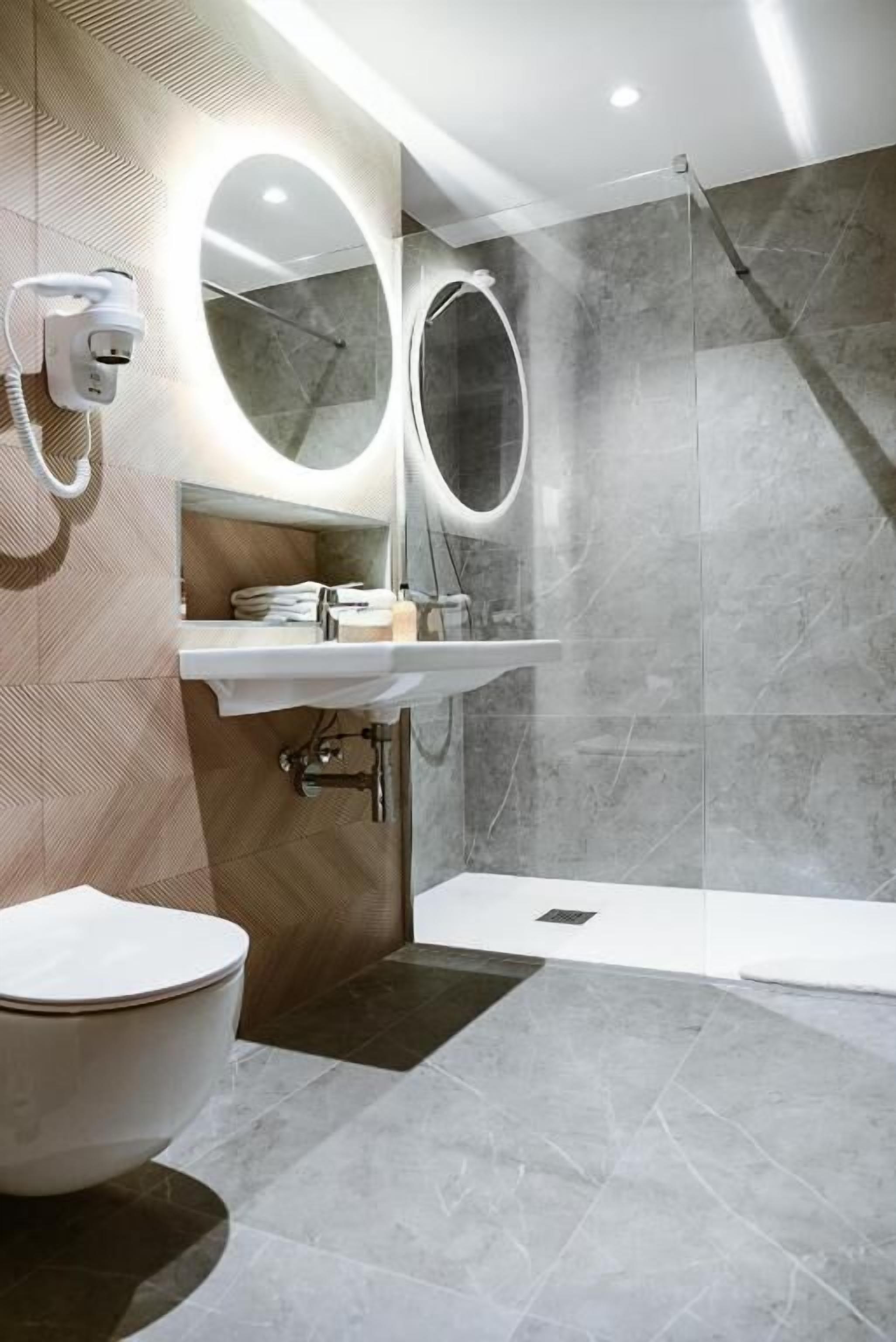 A modern bathroom with a toilet, sink, and shower.