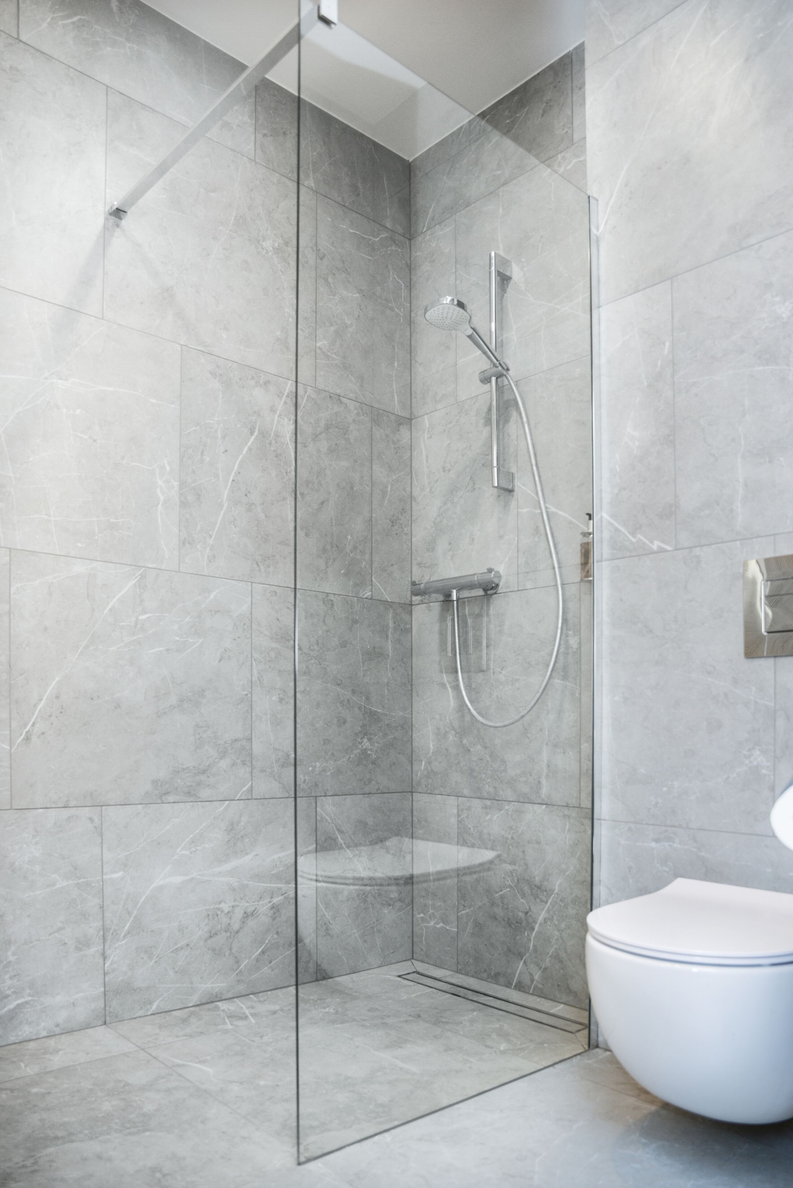 Une salle de bain moderne dotée d’une douche à parois de verre, de toilettes et d’un lavabo.