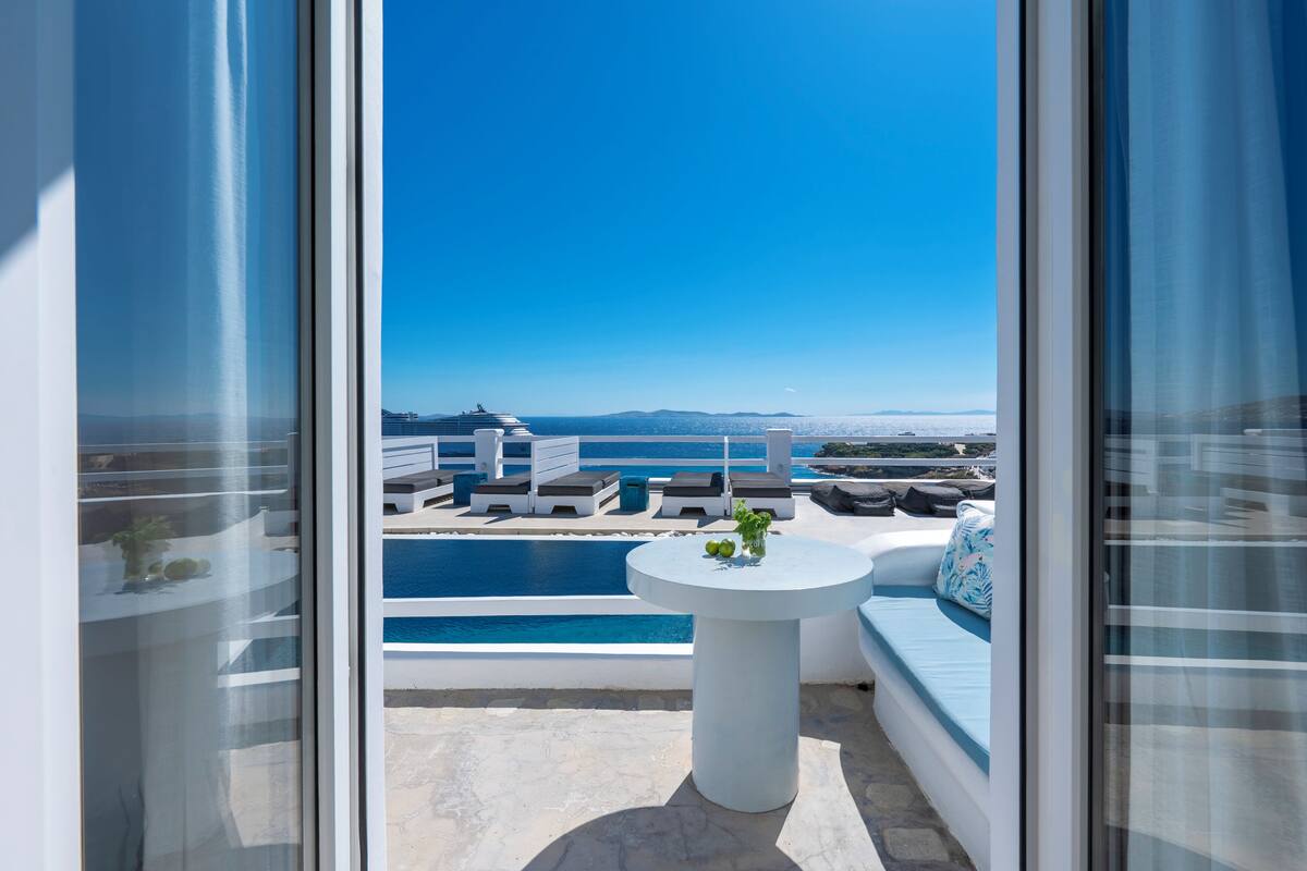 A balcony with a view of a pool and a distant cruise ship.
