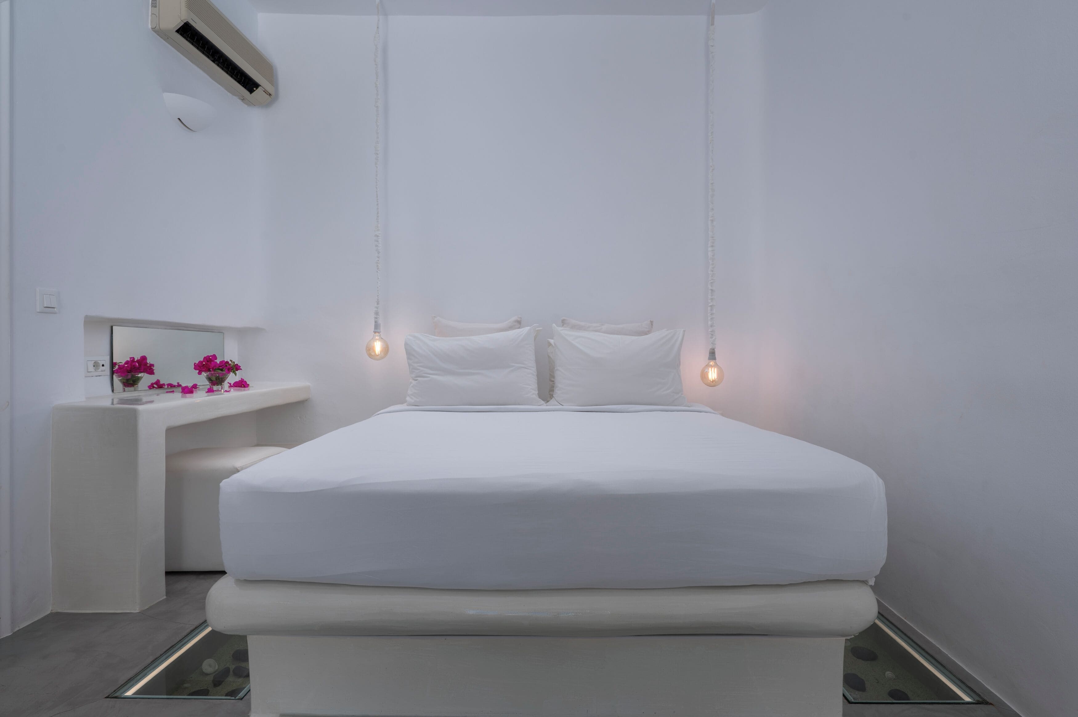 Un dormitorio minimalista con una cama grande, lámparas de noche y una mesita de noche con flores.