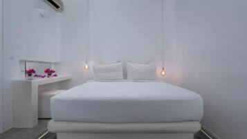 Un dormitorio minimalista con una cama grande, lámparas de noche y una mesita de noche con flores.