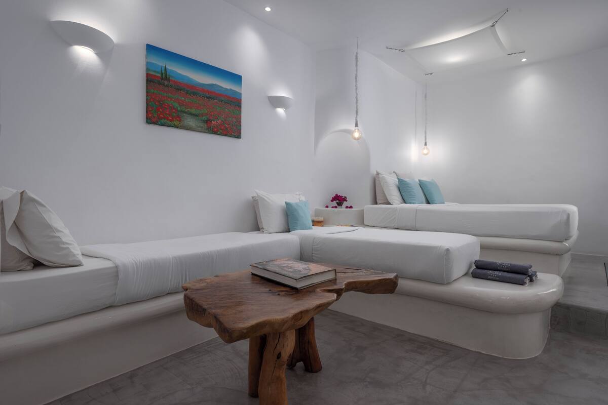 A modern living room with a white sofa, a wooden coffee table, and a painting on the wall.