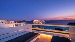 A rooftop terrace with lounge chairs, a pool, and a view of a cruise ship at sunset. - Flaskos Luxury Suites (Mykonos)