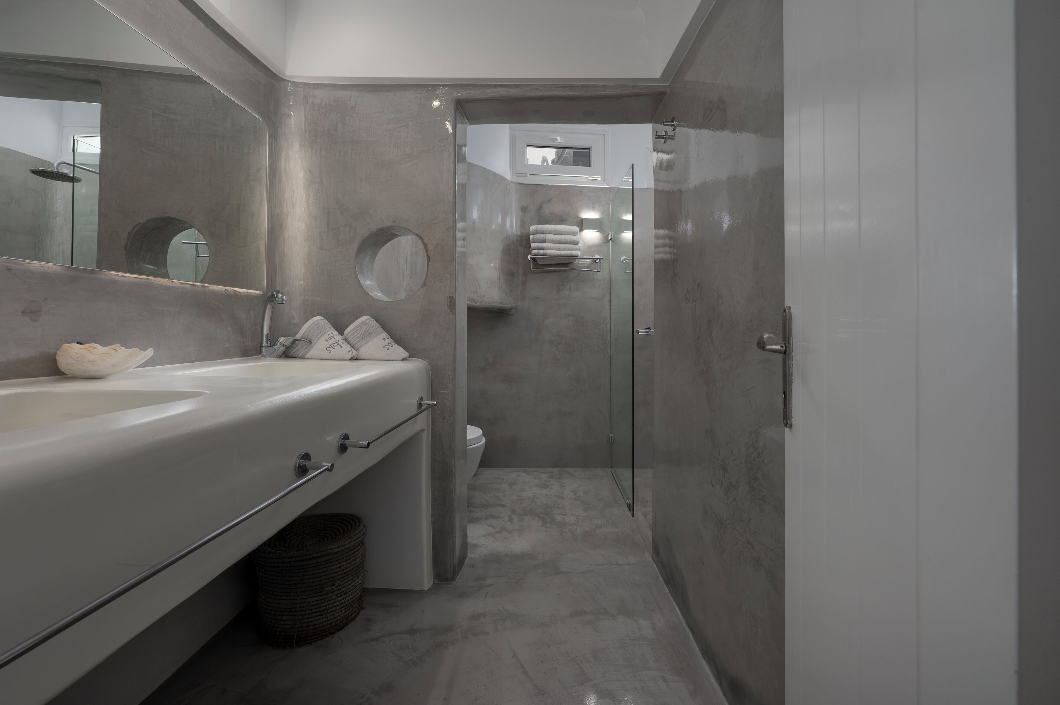 Een moderne badkamer met een groot bad, een ronde spiegel en een douche met glazen wanden.