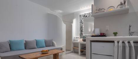 A modern, minimalist kitchen with white cabinetry, a built-in oven, and a small refrigerator.