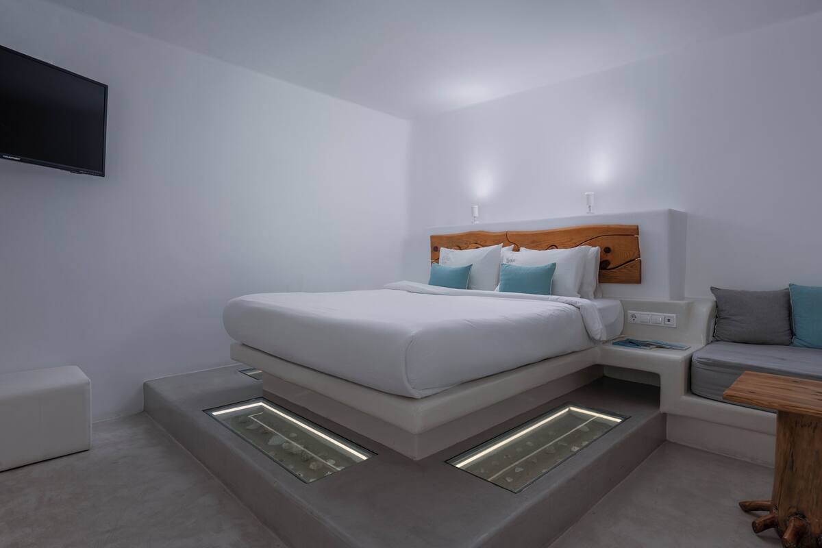 A modern bedroom with a bed, bedside tables, a TV, and built-in lighting.