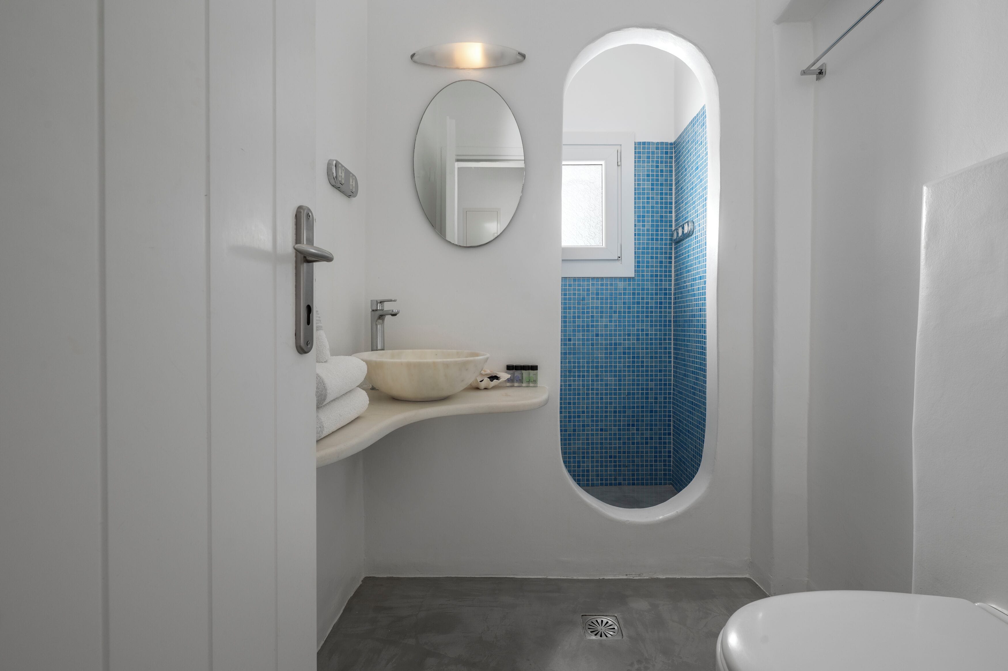 Une salle de bain moderne avec un lavabo blanc, un grand miroir, une baignoire aux carreaux bleus et des toilettes.