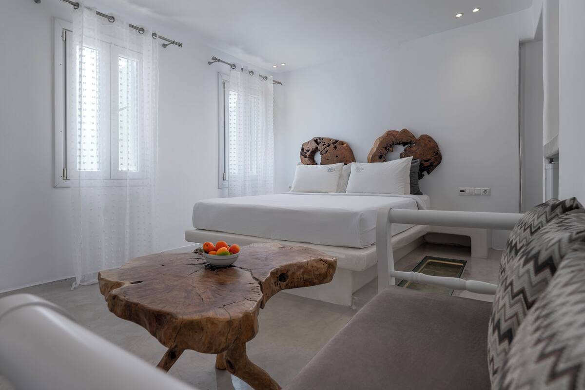 A modern bedroom with a bed, a wooden coffee table with fruit, and a unique wall decor piece.